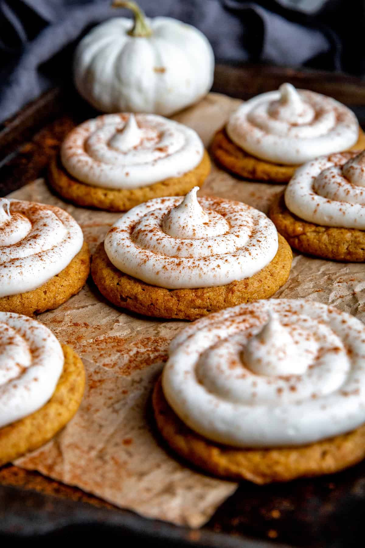 Pumpkin cookies topped with a swirl of cream cheese frosting.