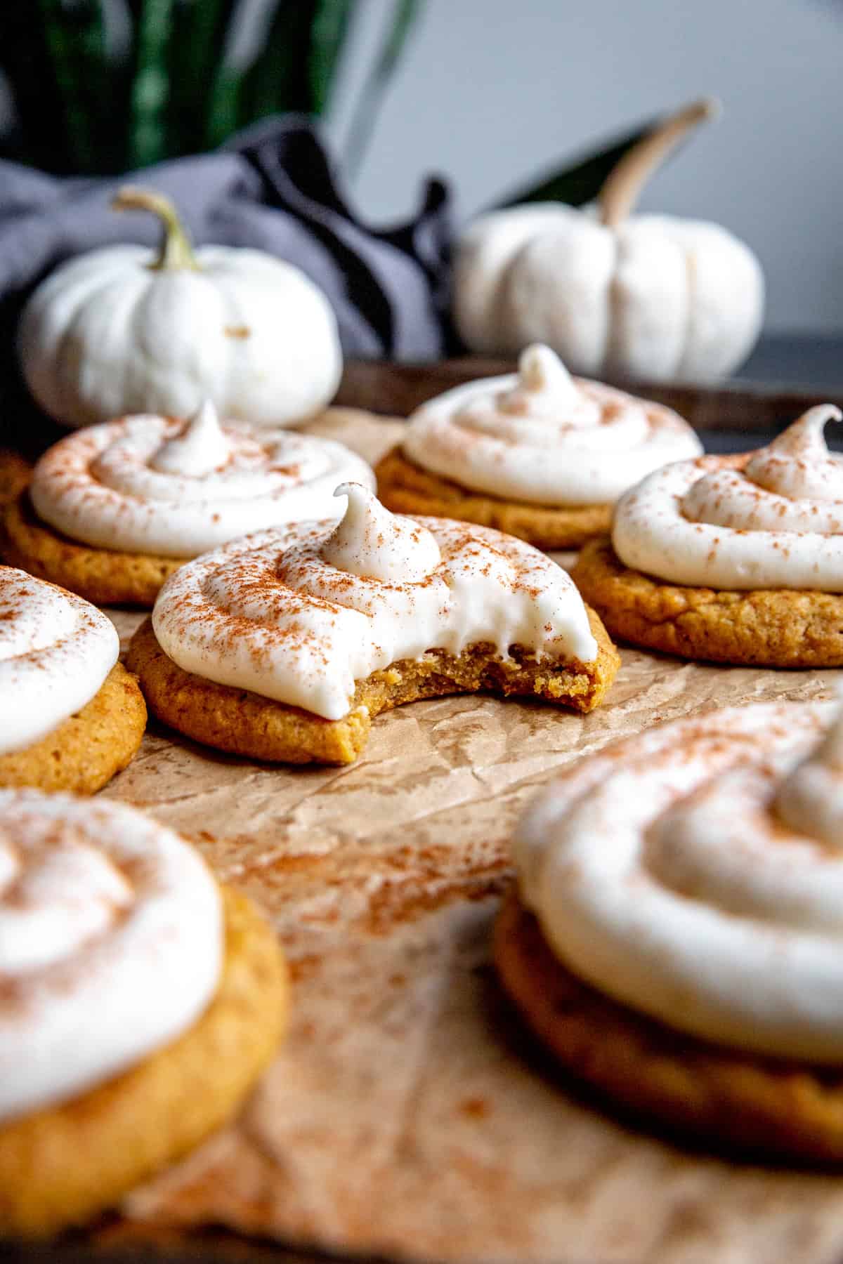 Frosted pumpkin cookie with a bite taken out of it.