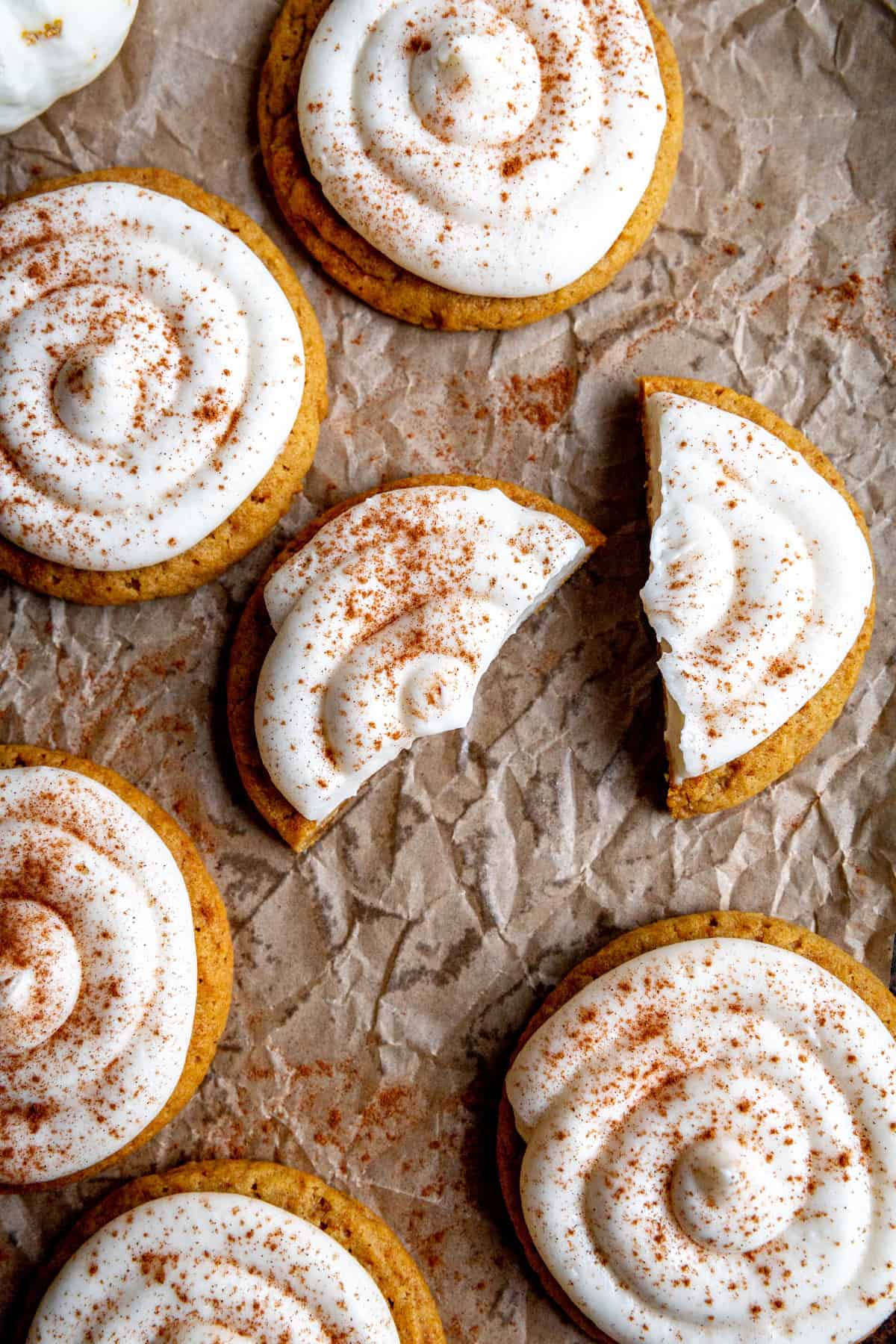 Frosted pumpkin cookie that has been cut in half.