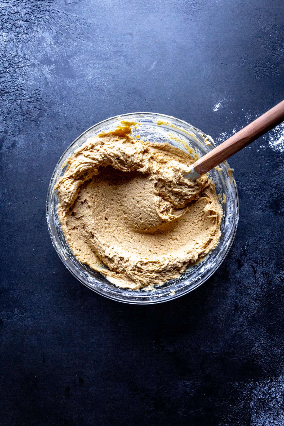 Glass bowl of pumpkin cookie dough and a rubber spatula.