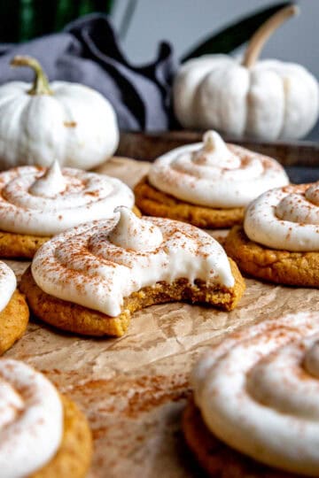Frosted pumpkin cookie with a bite taken out of it.