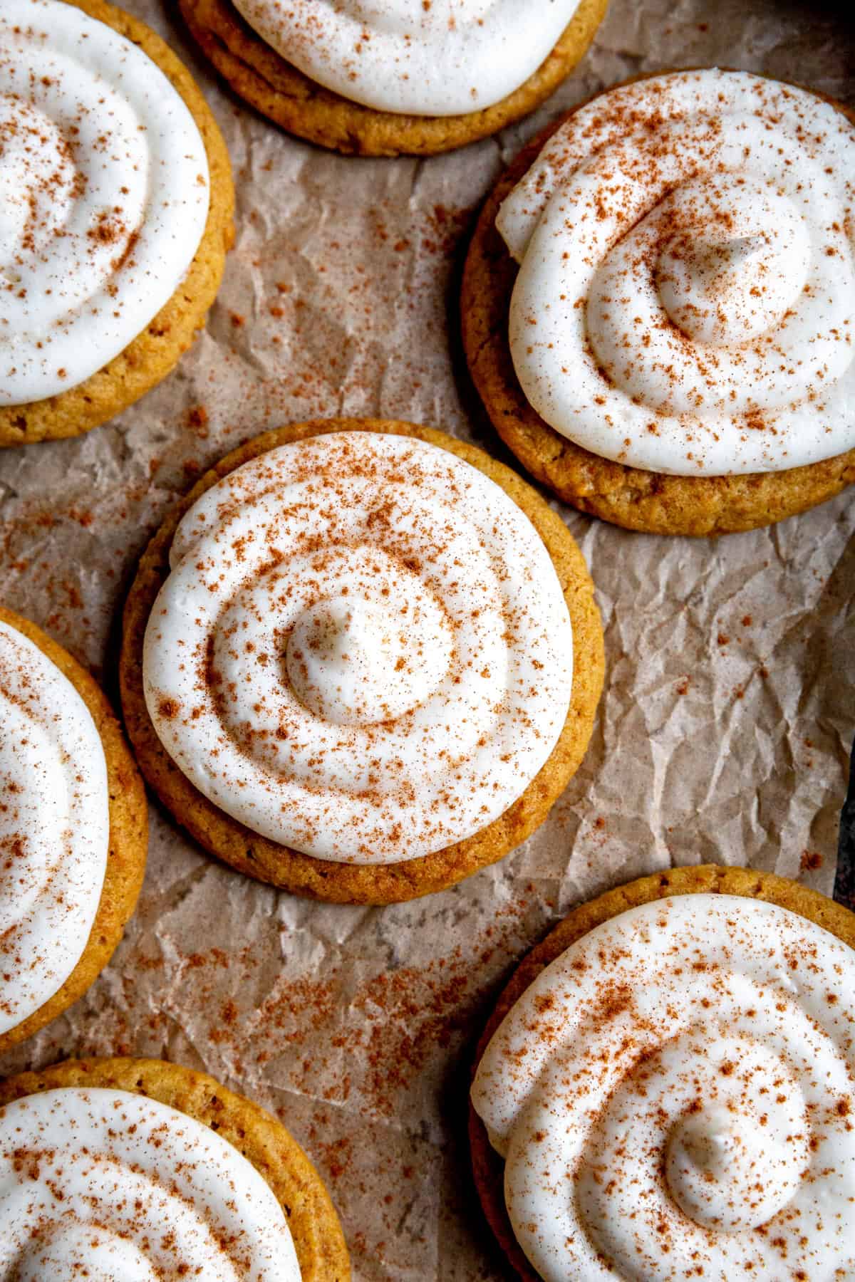 Pumpkin cookies topped with a swirl of cream cheese frosting.