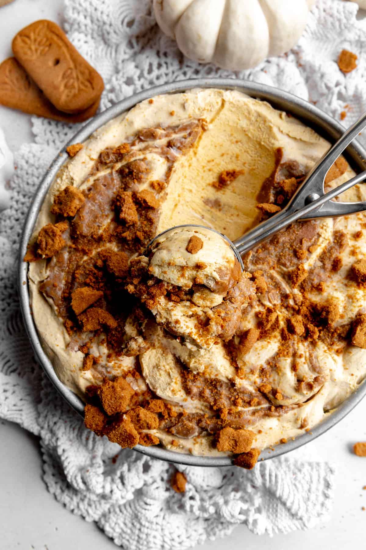 Ice cream scoop digging into a pan of pumpkin spice ice cream.