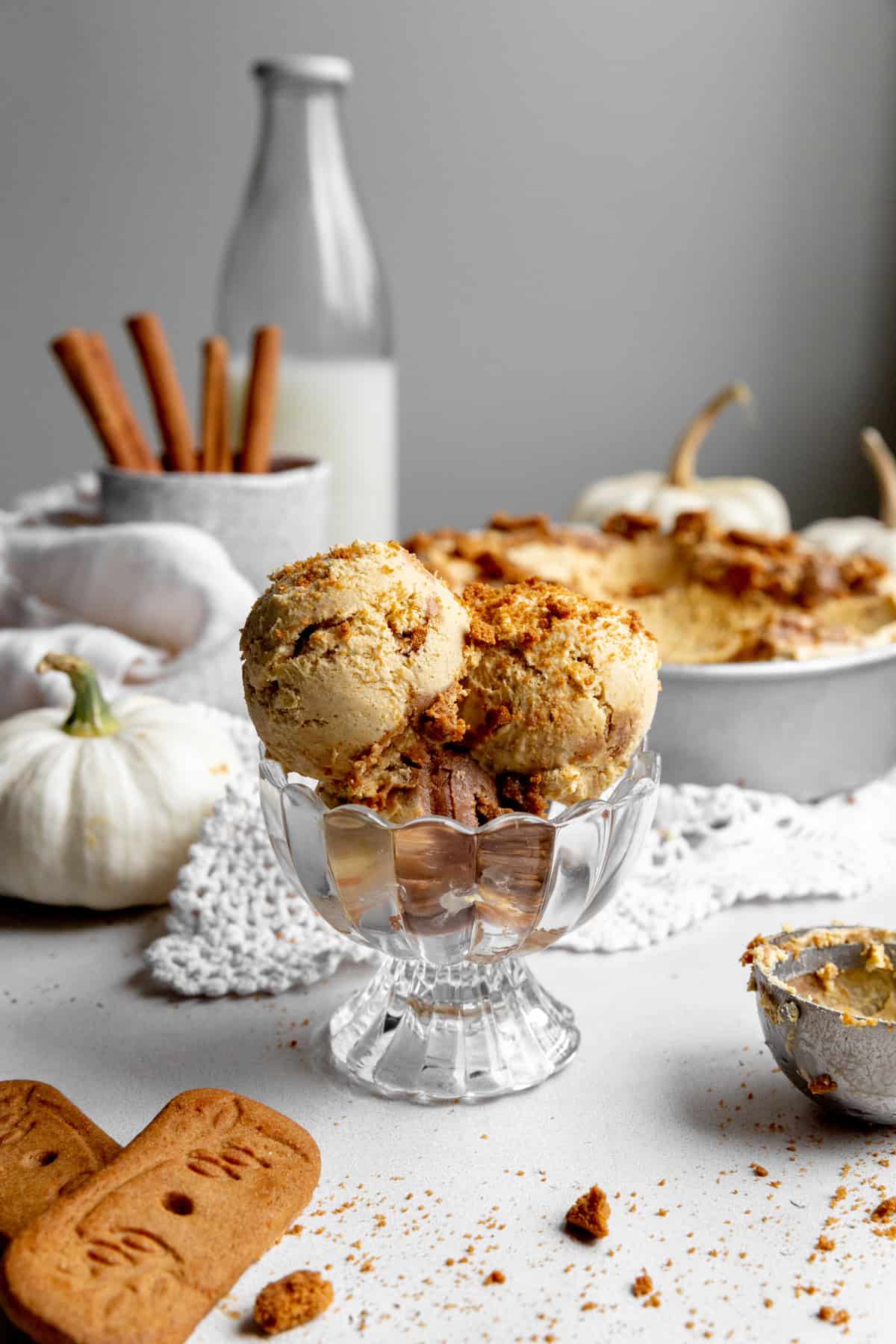 Dish of pumpkin spice ice cream, white pumpkins and a jug of milk.