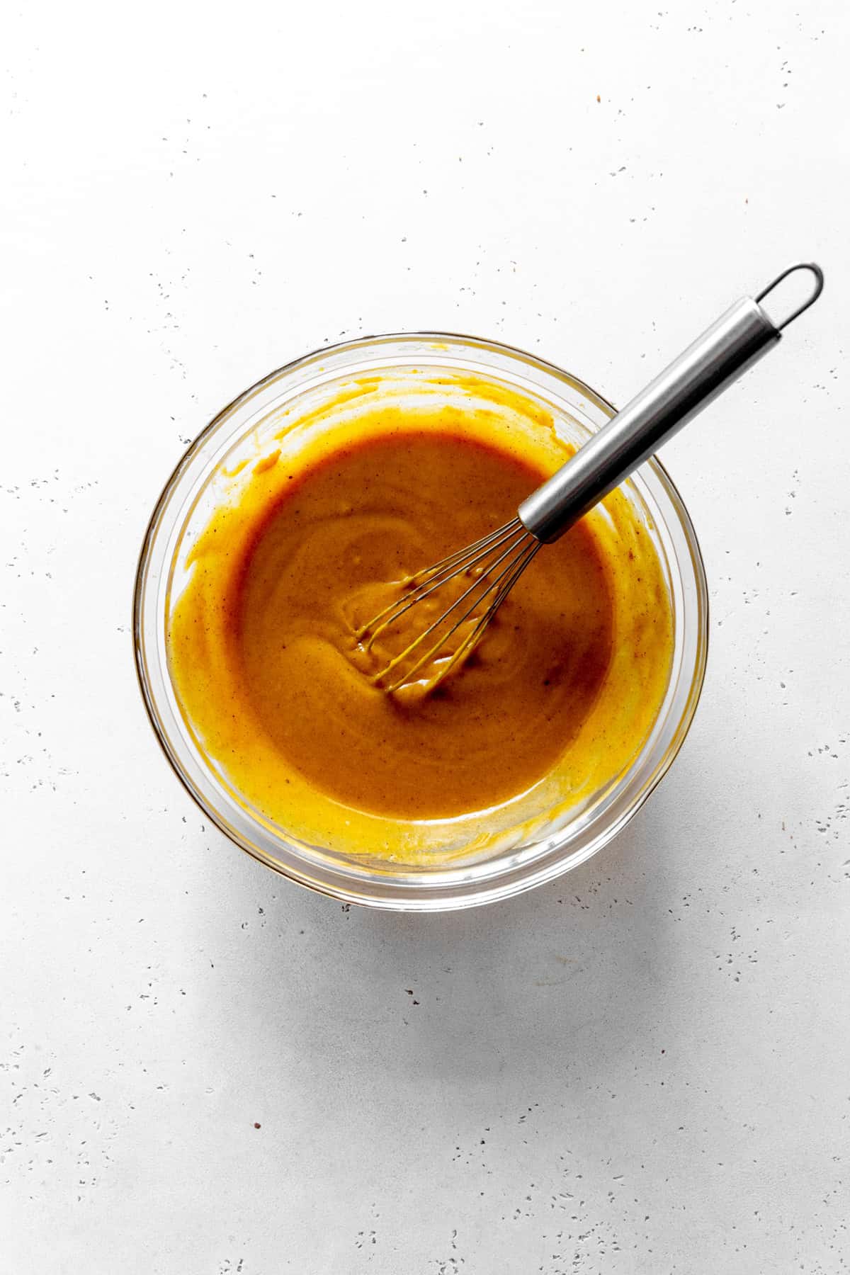 Pumpkin puree in a glass bowl with a wire whisk.
