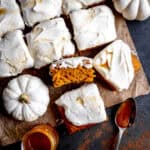 Slices of pumpkin cake, two small white pumpkins and a jar of caramel sauce.
