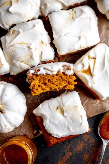 Slices of pumpkin cake, two small white pumpkins and a jar of caramel sauce.