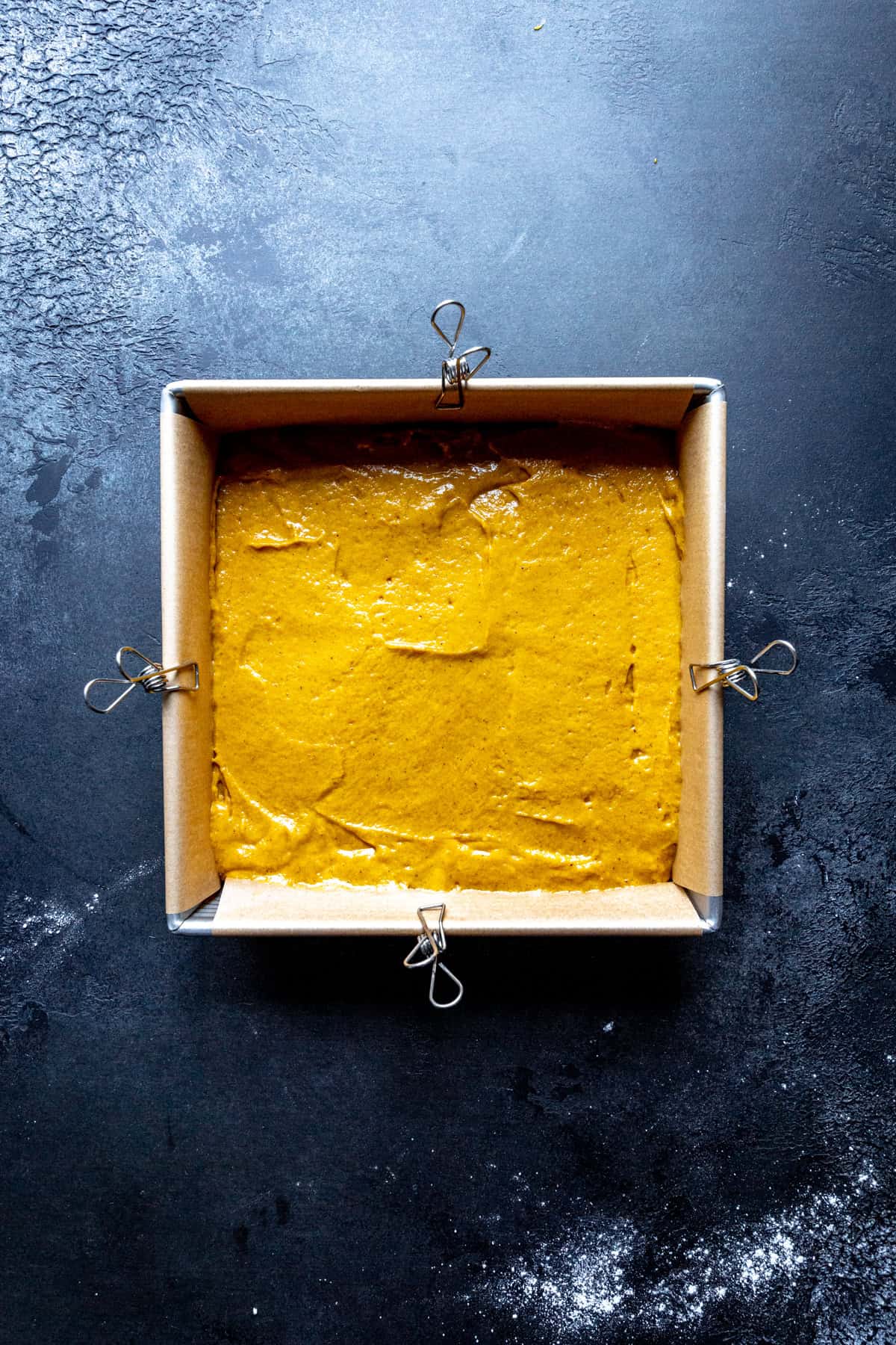 Pumpkin cake batter in a square pan.