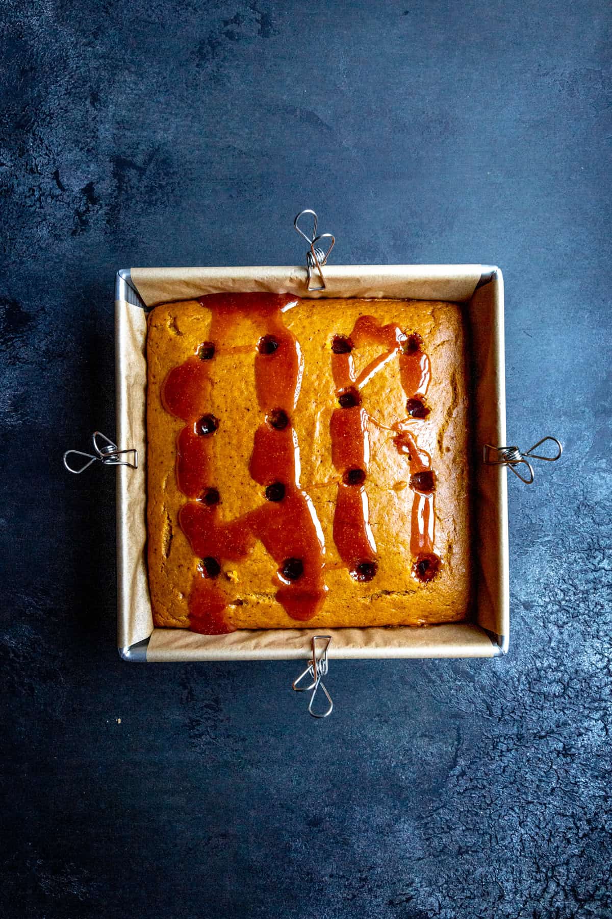 Pumpkin cake in a square pan with caramel drizzled over the top.