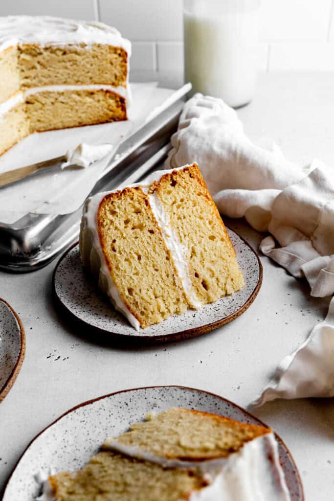 Slices of vanilla cake on plates and a jug of milk.