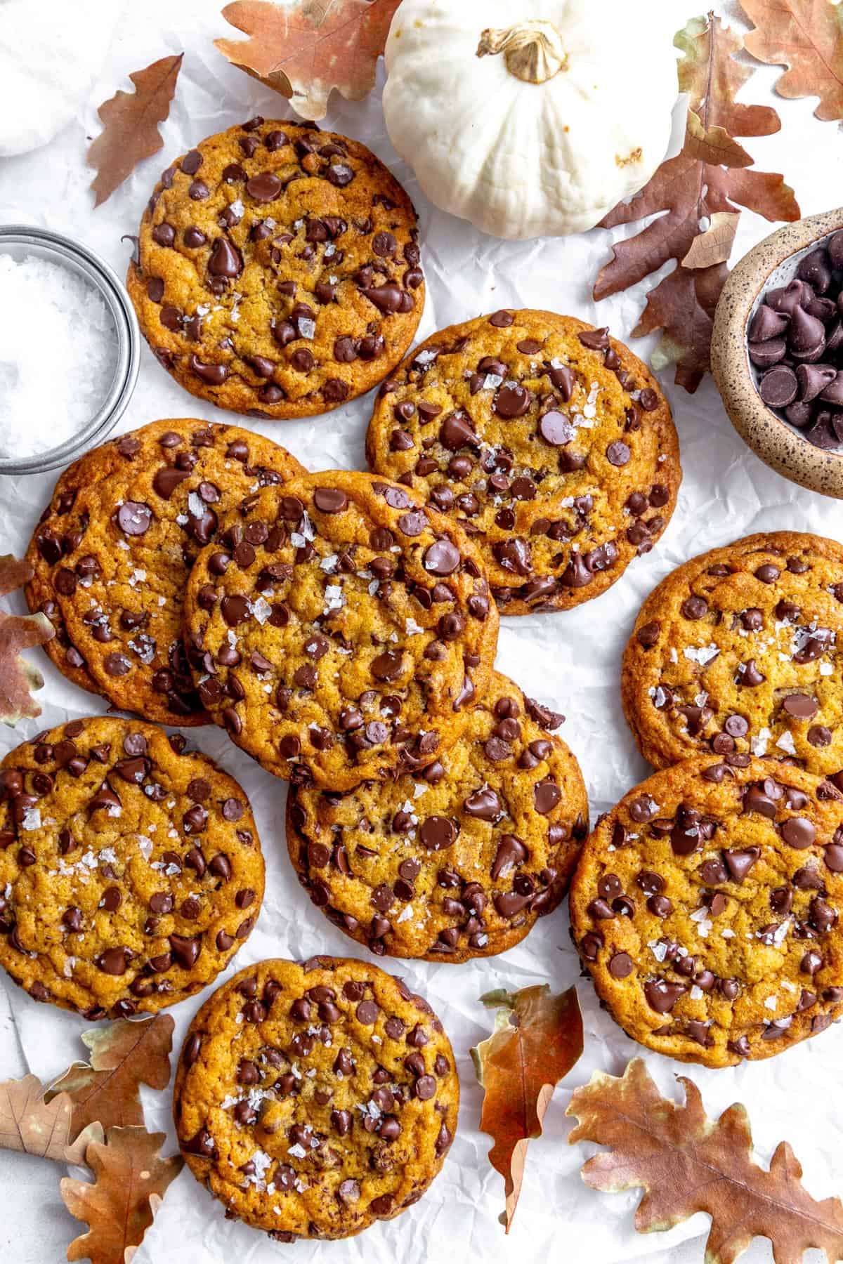 Pumpkin chocolate chip cookies, a white pumpkin and a cup of chocolate chips.