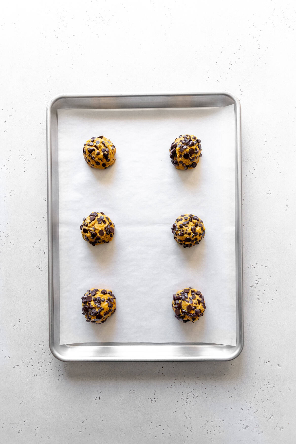 Unbaked pumpkin chocolate chip cookies on a baking sheet.