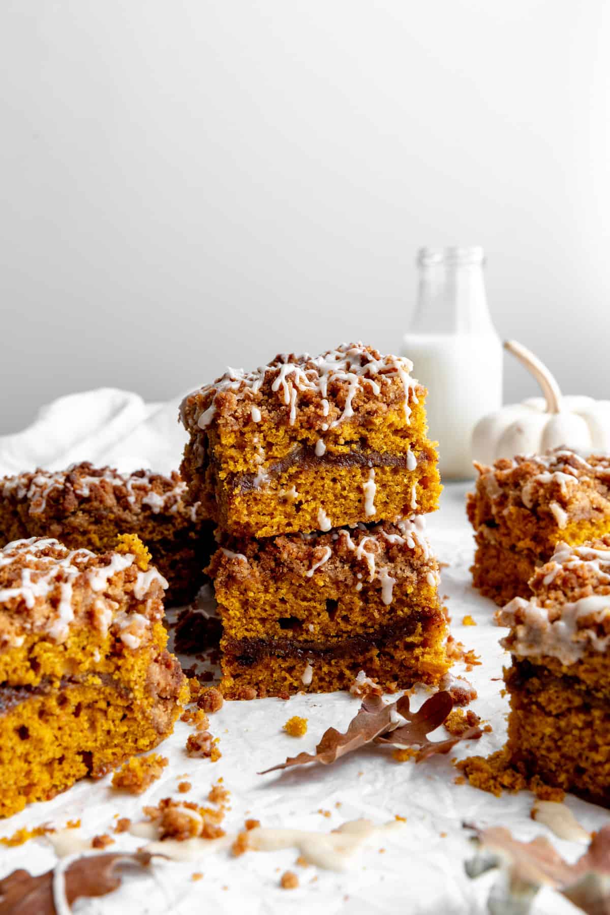 Stacked sliced of pumpkin coffee cake and a jug of milk.