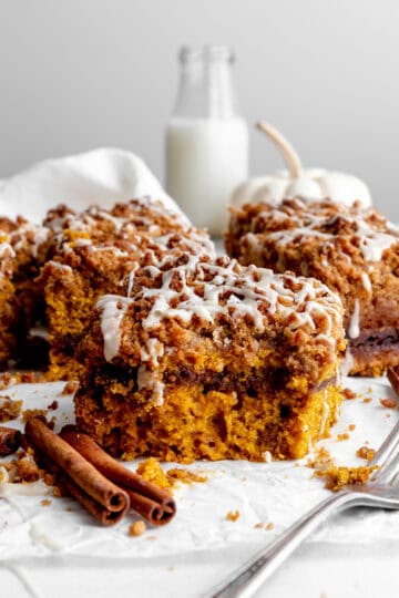 Slice of pumpkin coffee cake with a bite missing and a jug of milk.