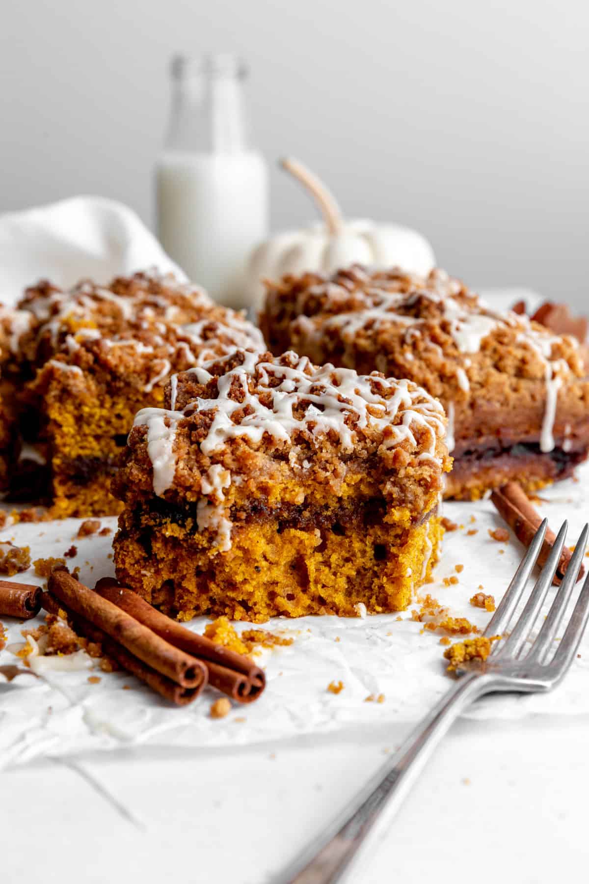 Slice of pumpkin coffee cake with a bite missing and a jug of milk.
