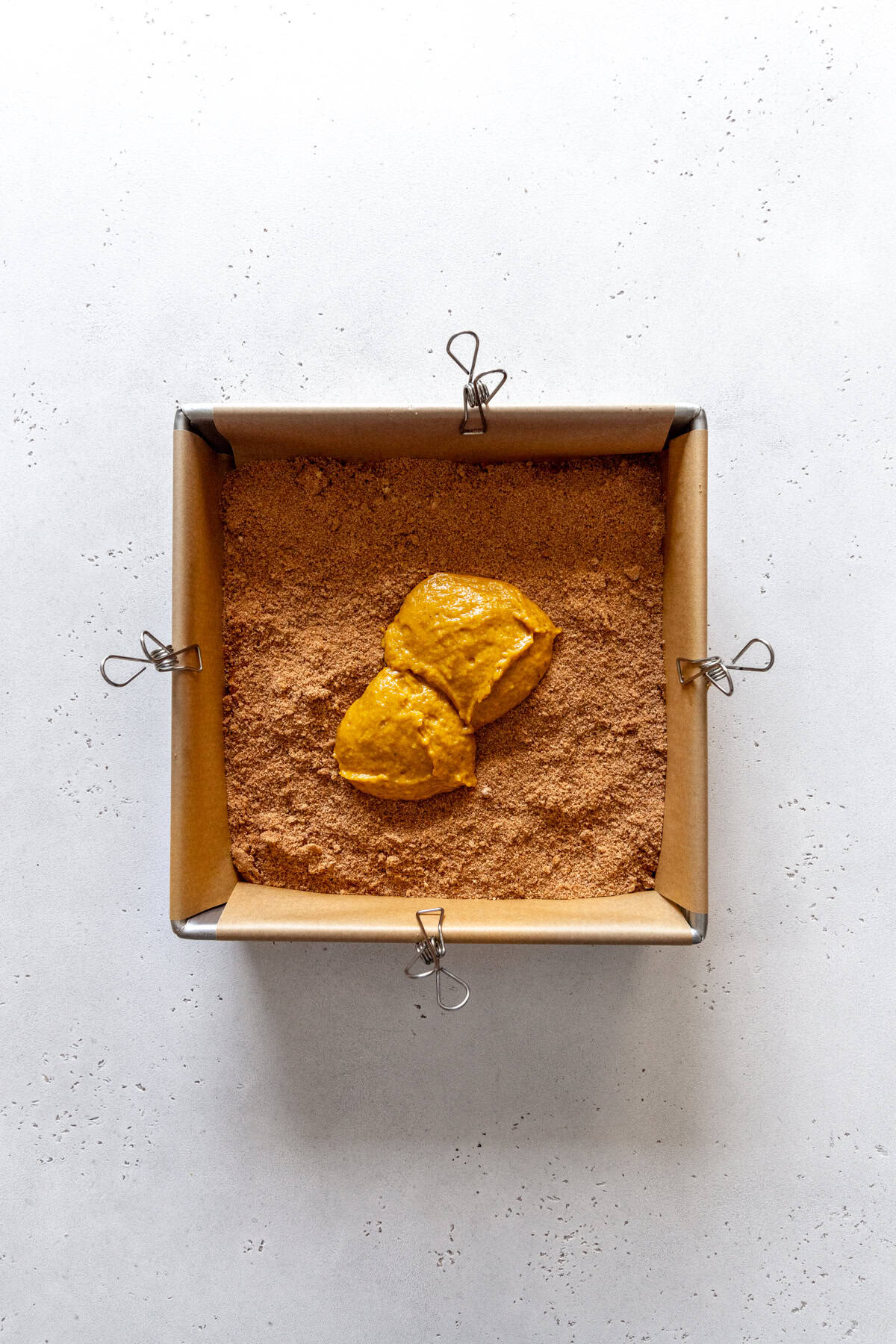 Square pan of pumpkin coffee cake batter layered with cinnamon sugar.