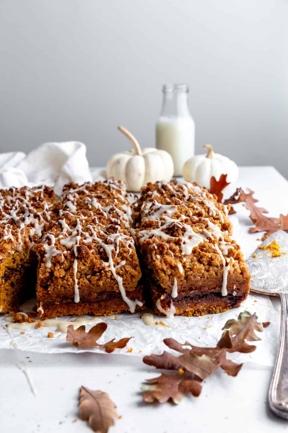 Pumpkin coffee cake, two white pumpkins and a jug of milk.
