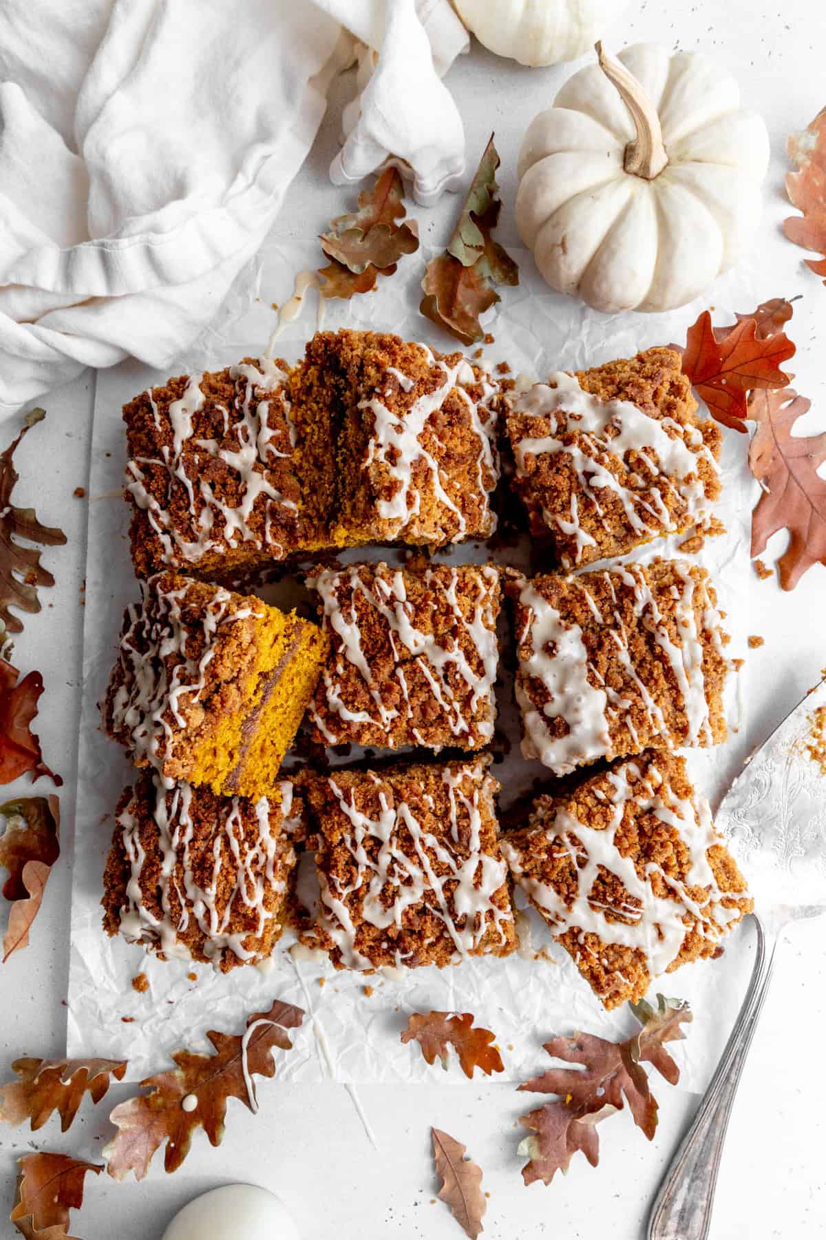 Sliced pumpkin coffee cake, a white pumpkin and a linen napkin.