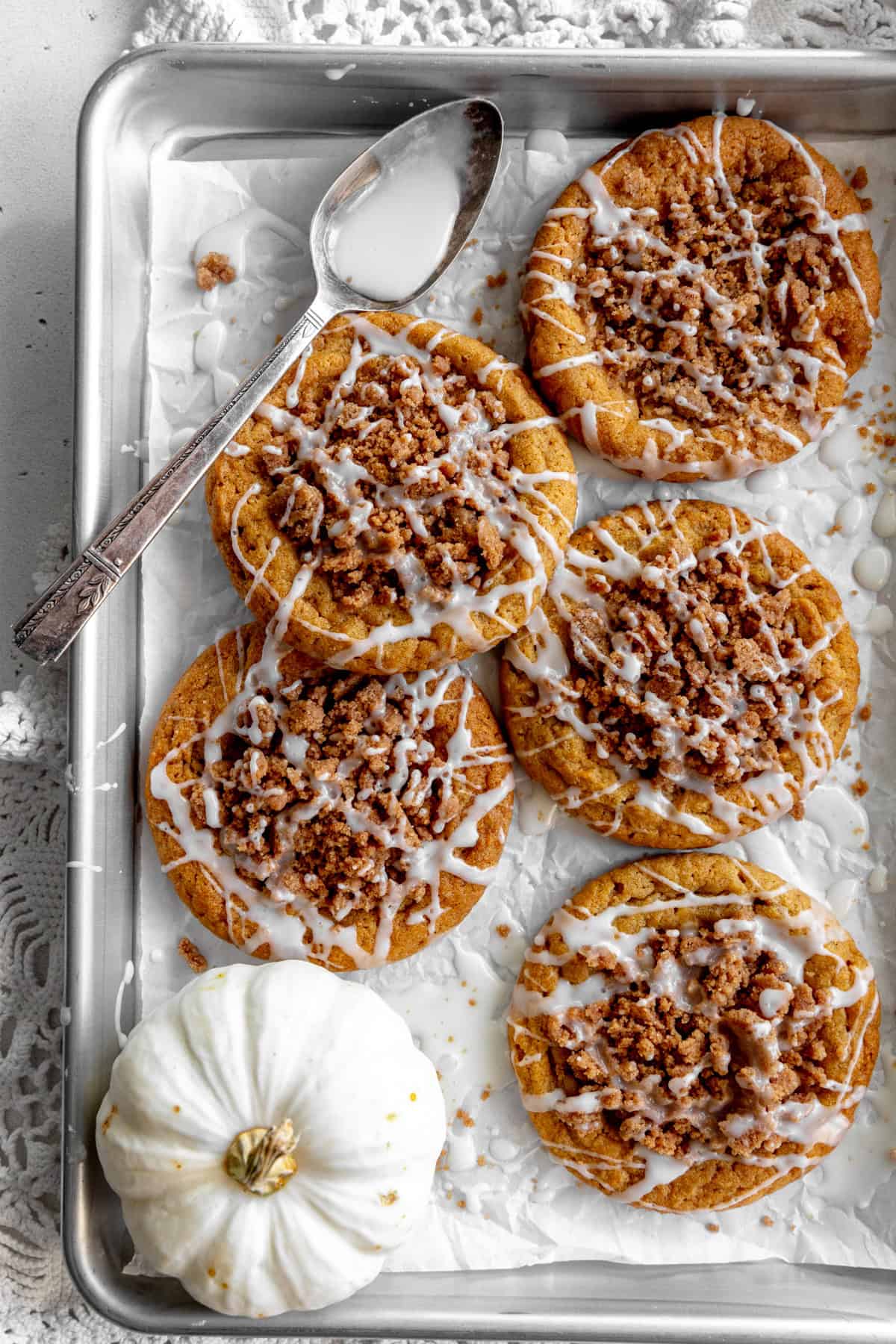 Pumpkin coffee cake cookies on a baking sheet with a white pumpkin.