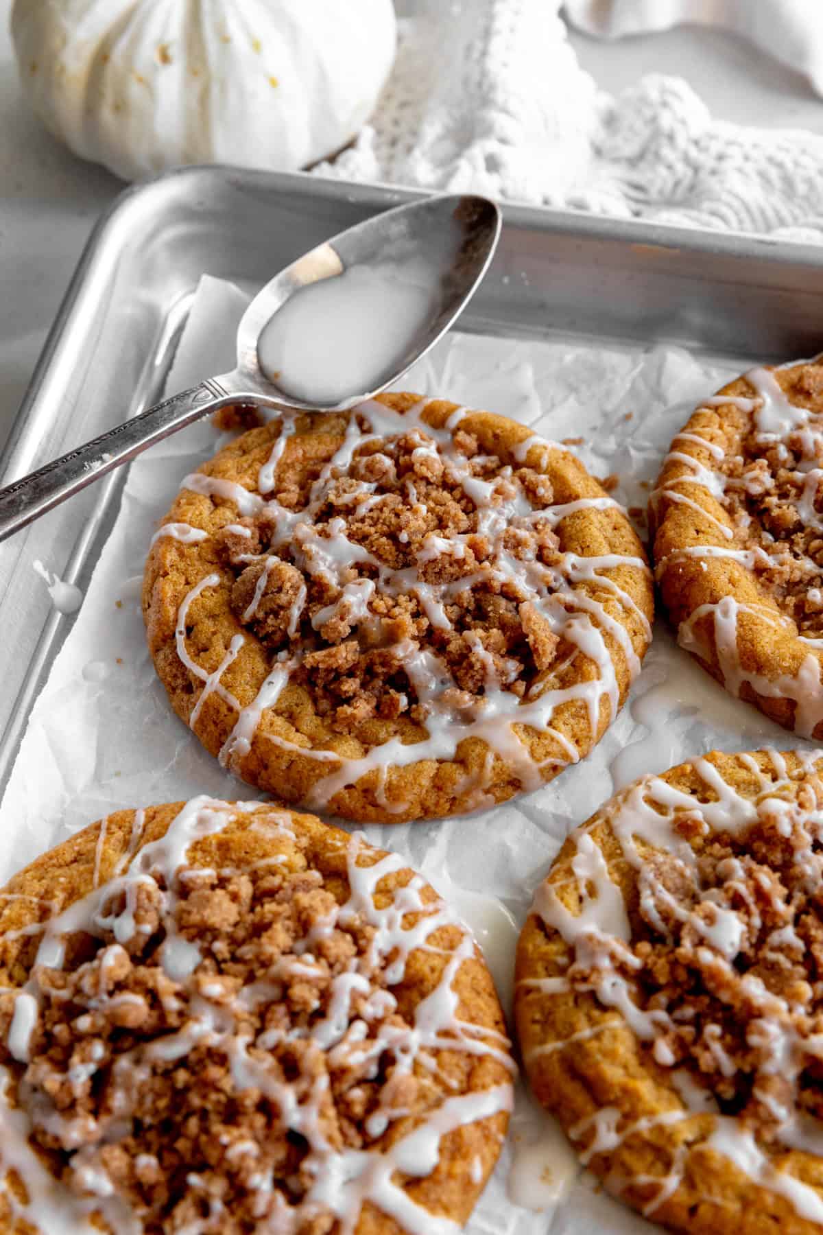 Spoon dripping glaze on a pumpkin cookie.