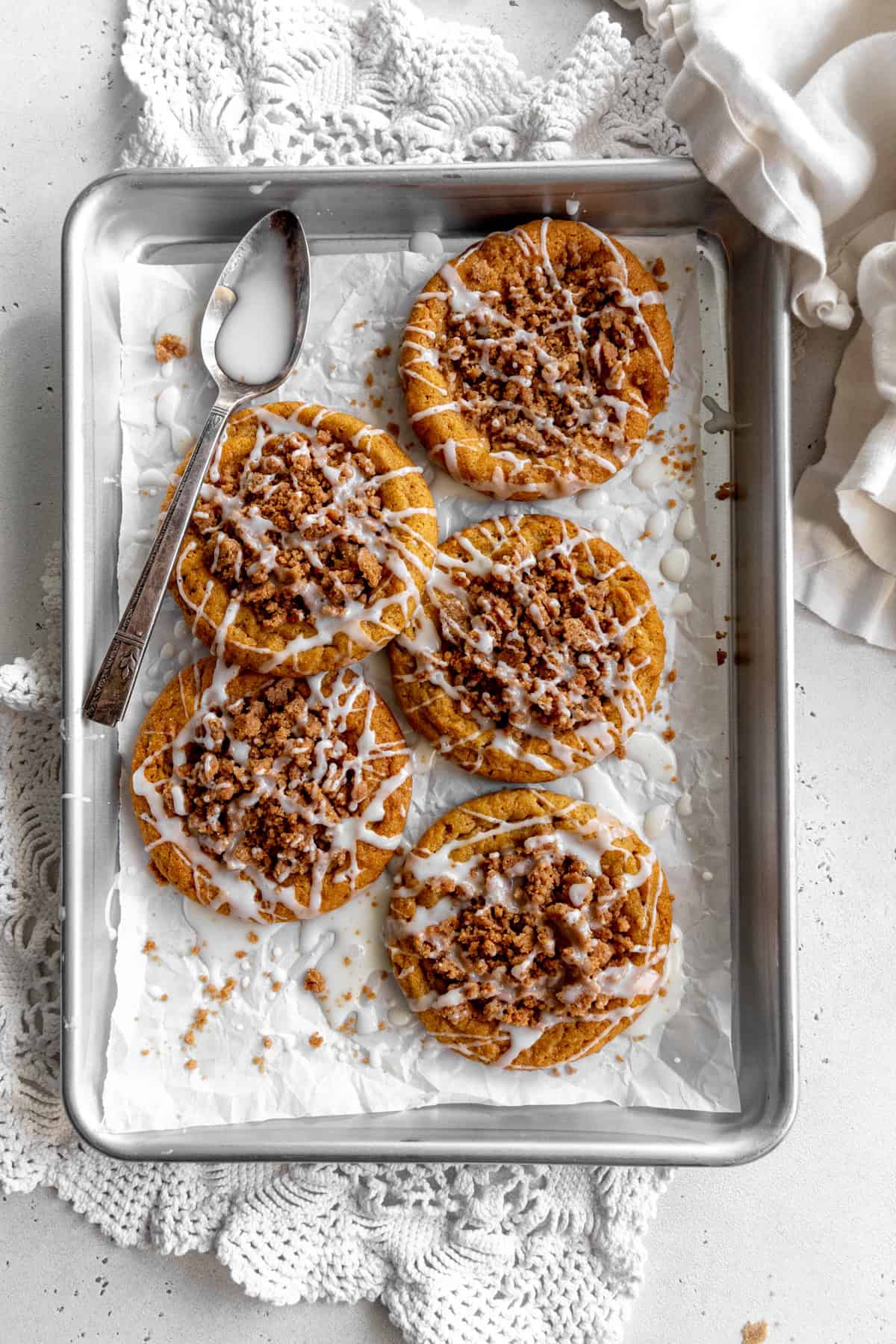 Pumpkin coffee cake cookies on a baking sheet and a spoon covered in glaze.