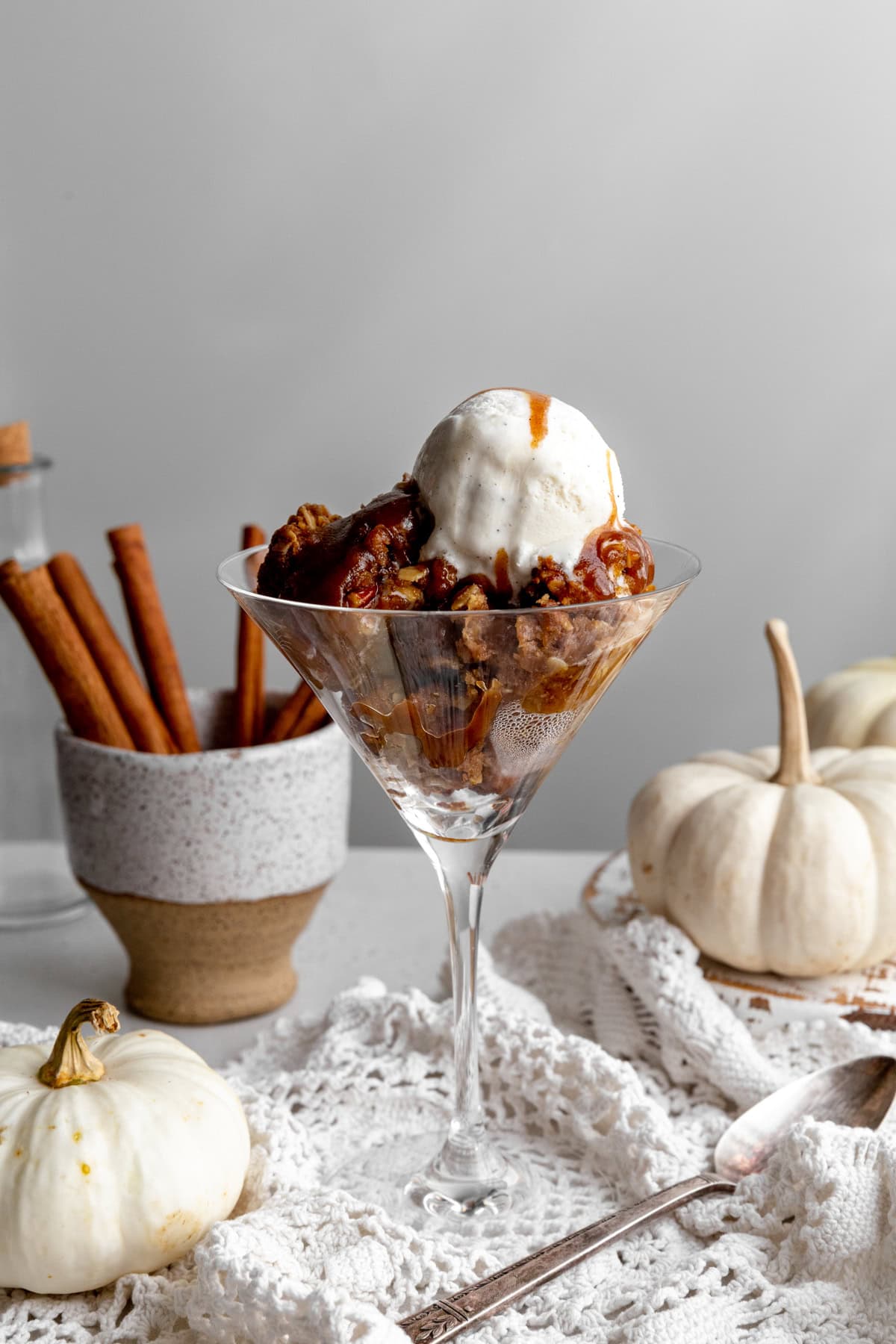 Pumpkin crisp topped with vanilla ice cream and a cup of cinnamon sticks.