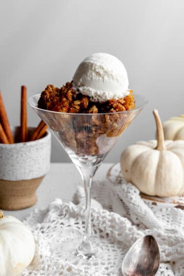 Pumpkin crisp in a martini glass topped with a scoop of vanilla ice cream.